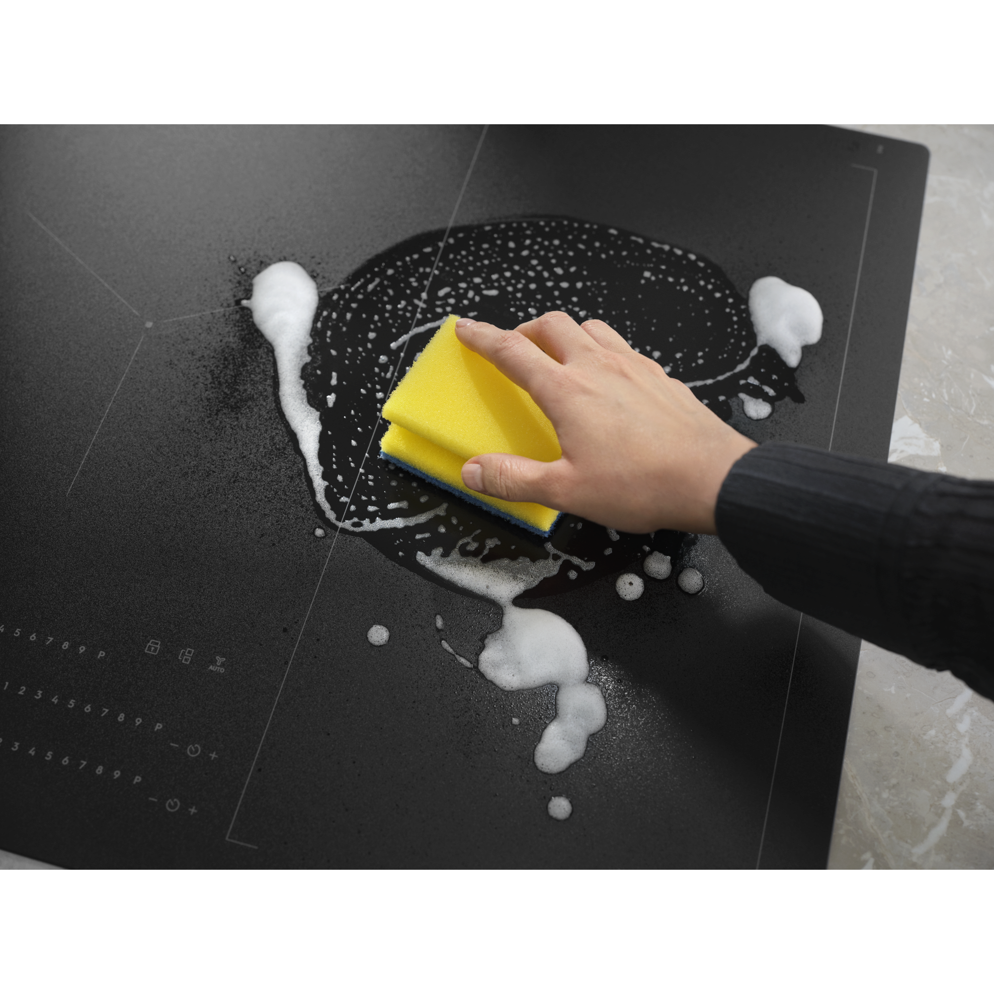 Hob Cleaner being applied with foam and sponge, highlighting its easy-to-clean feature.