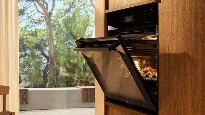  En Electrolux-ugn inbyggd i en elegant träpanel med ugnsluckan på glänt.