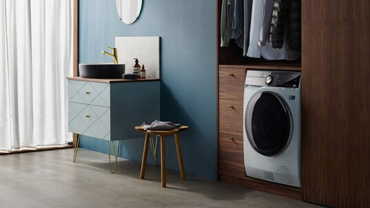 En kombinerad tvättmaskin och torktumlare från Electrolux placerad i en garderob under ett klädstativ.