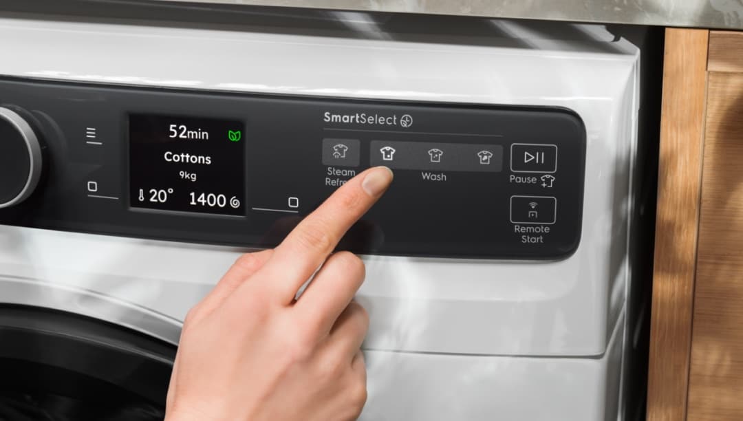 Hand som justerar kontrollpanelen på en tvättmaskin från Electrolux.