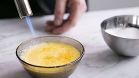 En bagare som karamelliserar sockret på crème bruléen med en liten brännare