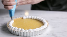 En bagare häller i den släta krämen i pajdegen