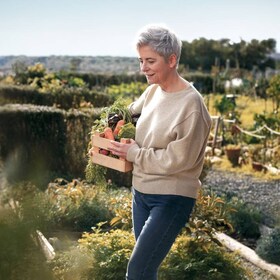 Kvinna plockar grönsaker i trädgård