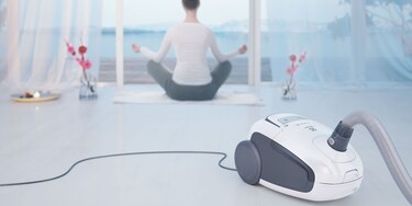 Kvinna som utövar yoga intill dammsugare