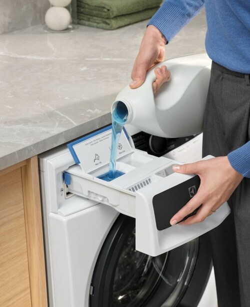 En person häller tvättmedel i en tvättmaskin från Electrolux.