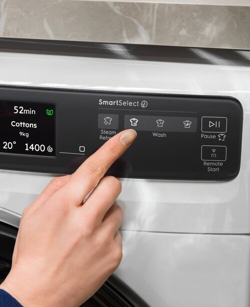 Person som justerar kontrollpanelen på en tvättmaskin från Electrolux.