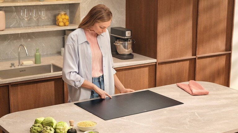 Kvinna som ska laga mat på spishällen