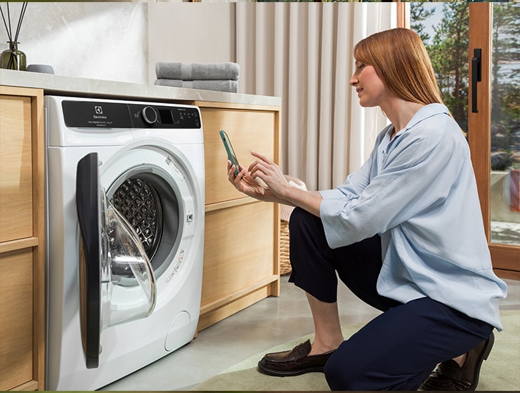 Woman holding a phone in front of washing machine