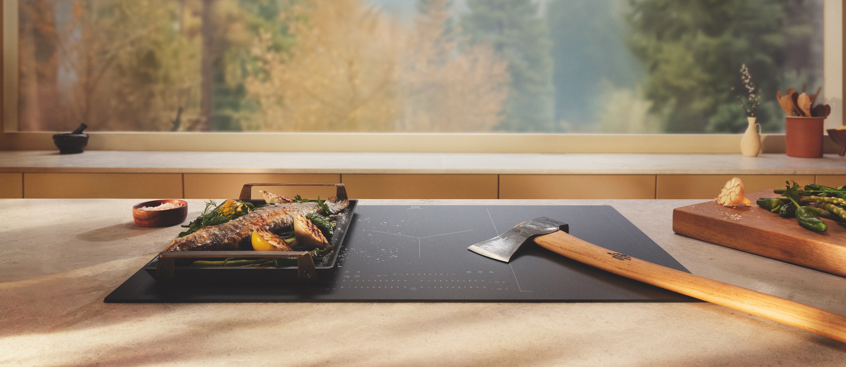 An axe is placed on an induction hob with SaphirMatt surface next to grilled food.
