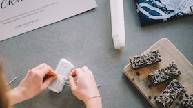 Händer som knyter rosett på en present