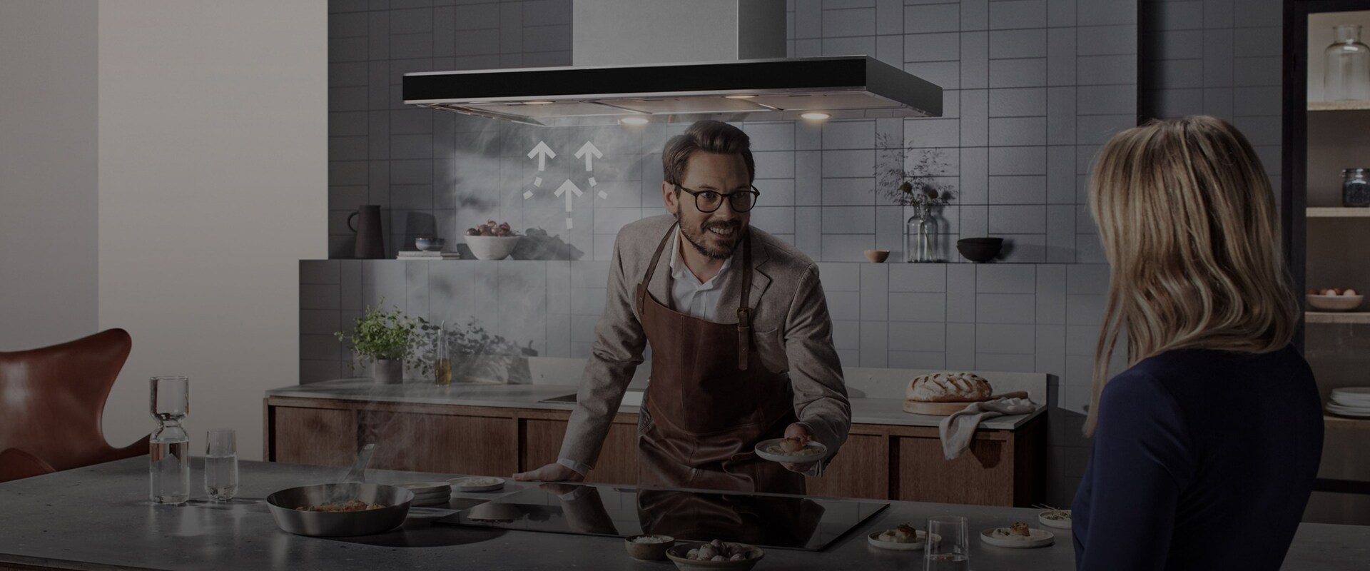 På köksön finns en integrerad induktionshäll där en stekpanna används och tydlig ånga stiger upp från maten.