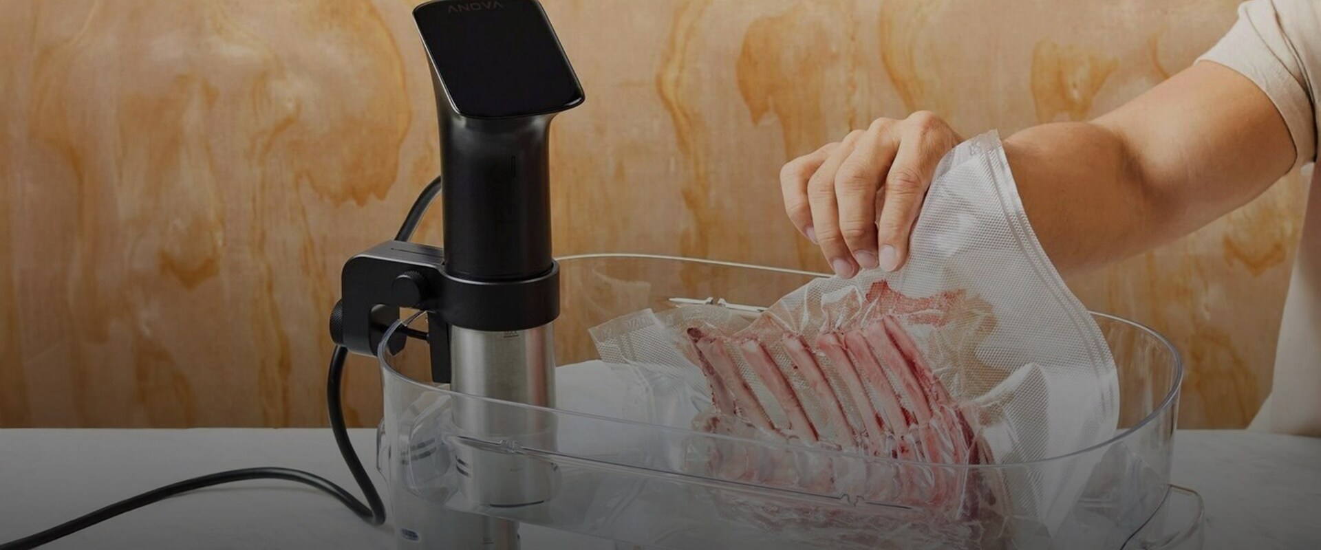 Vakuumförpackat kött sänks ned i behållare med vatten och sous vide-stav