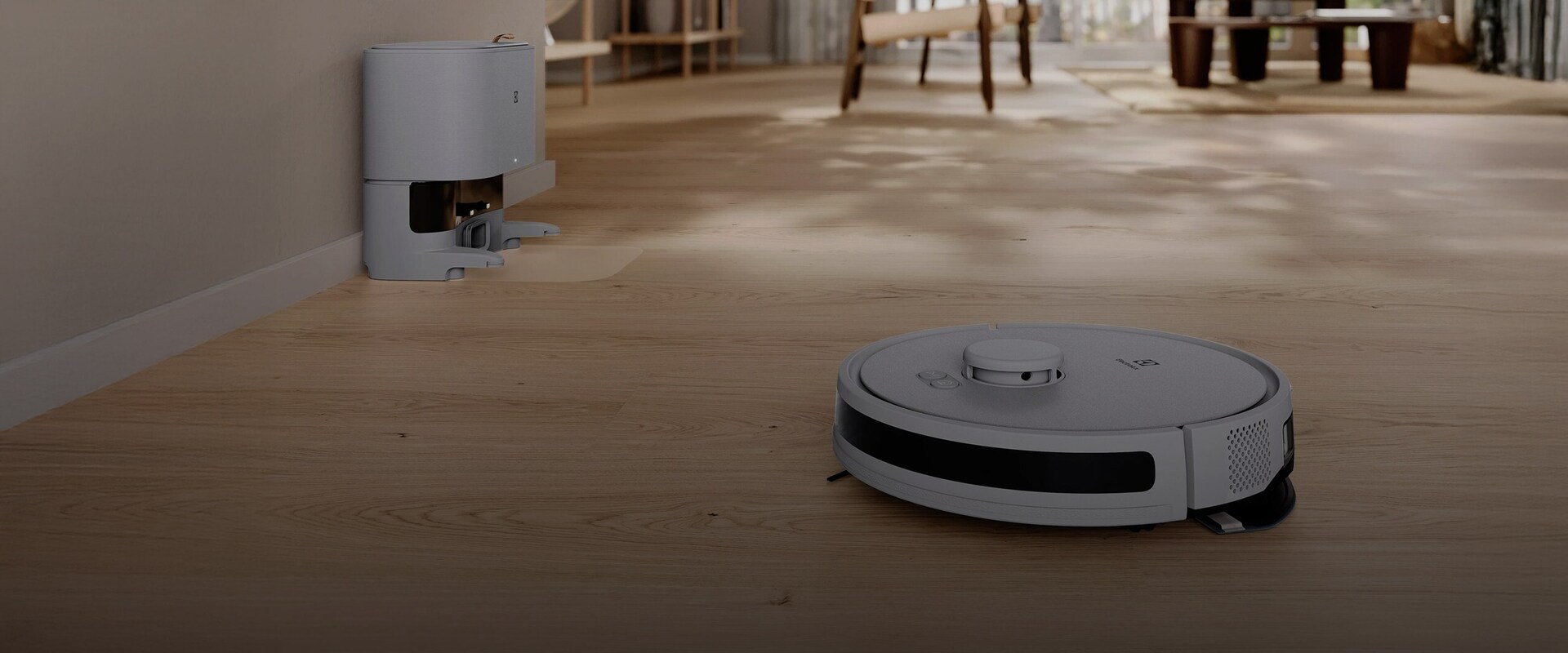 Självgående Electrolux robotdammsugare som rengör ett ljust trägolv i ett öppet och modernt vardagsrum.
