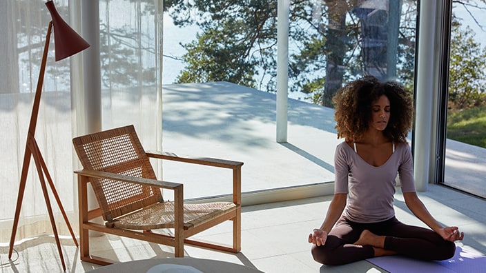 En kvinna utövar yoga i sitt vardagsrum, med optimal luft och behagligt inomhusklimat. 