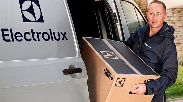 En man som lastar ur en vitvara från en bil