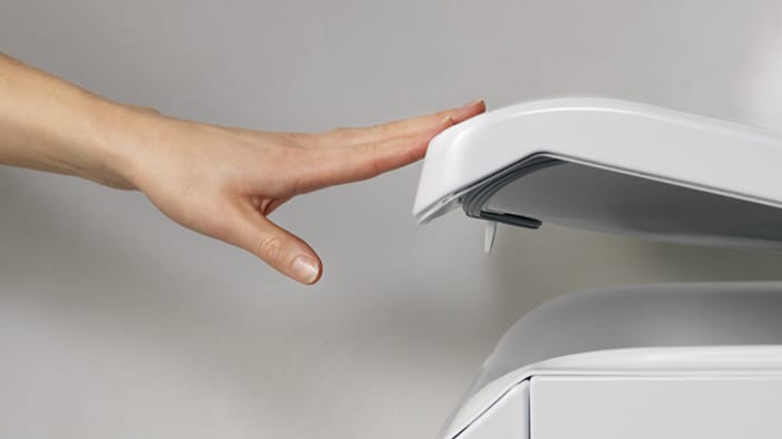 Hand som stänger en toppmatad tvättmaskin