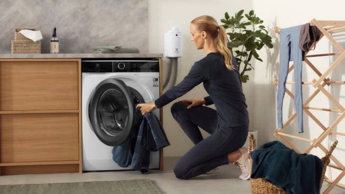kvinna lägger in tvätt i en tvättmaskin